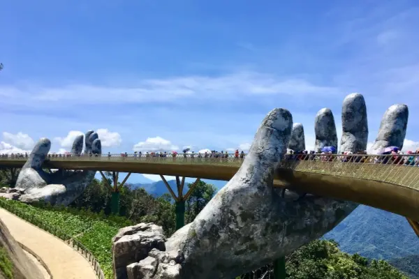 Le Pont d'Or unique tenu par des mains de pierre géantes, entouré d'une verdure luxuriante et de montagnes sous un ciel bleu clair, une attraction touristique populaire au Vietnam.