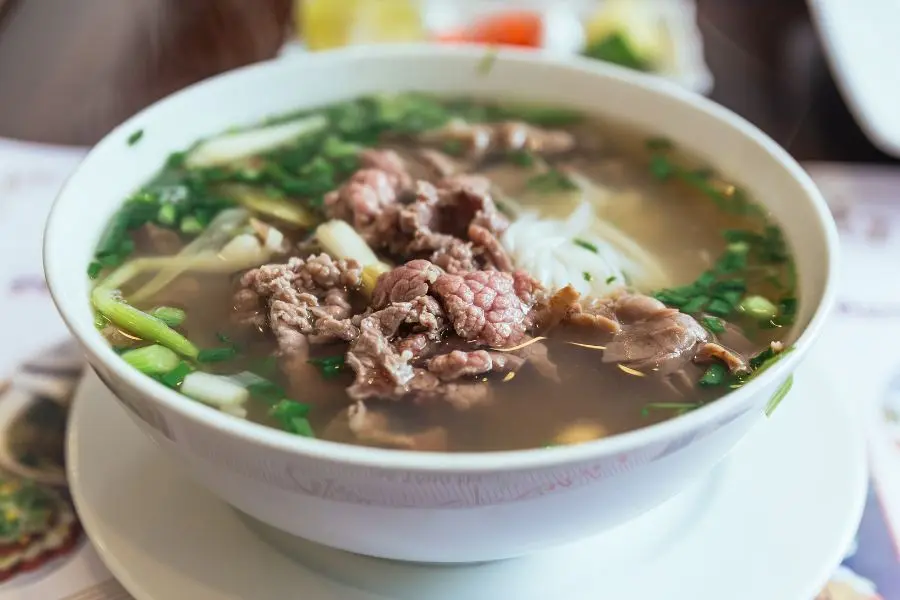 Un bol fumant de pho vietnamien, composé de bœuf tendre, d'herbes fraîches et de nouilles de riz dans un bouillon onctueux. Ce plat emblématique est un incontournable pour un voyage au Vietnam en 2026.